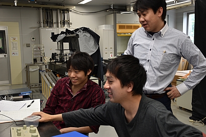 Professor Takahashi enjoys talking with students while performing an experiment