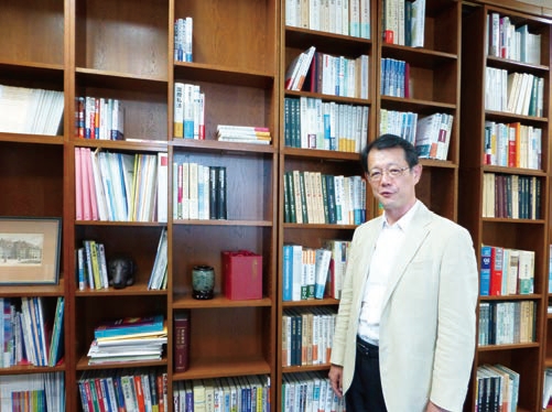 書棚の前に立つ玉井教授