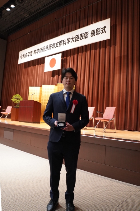 メダルを持つ松久准教授
